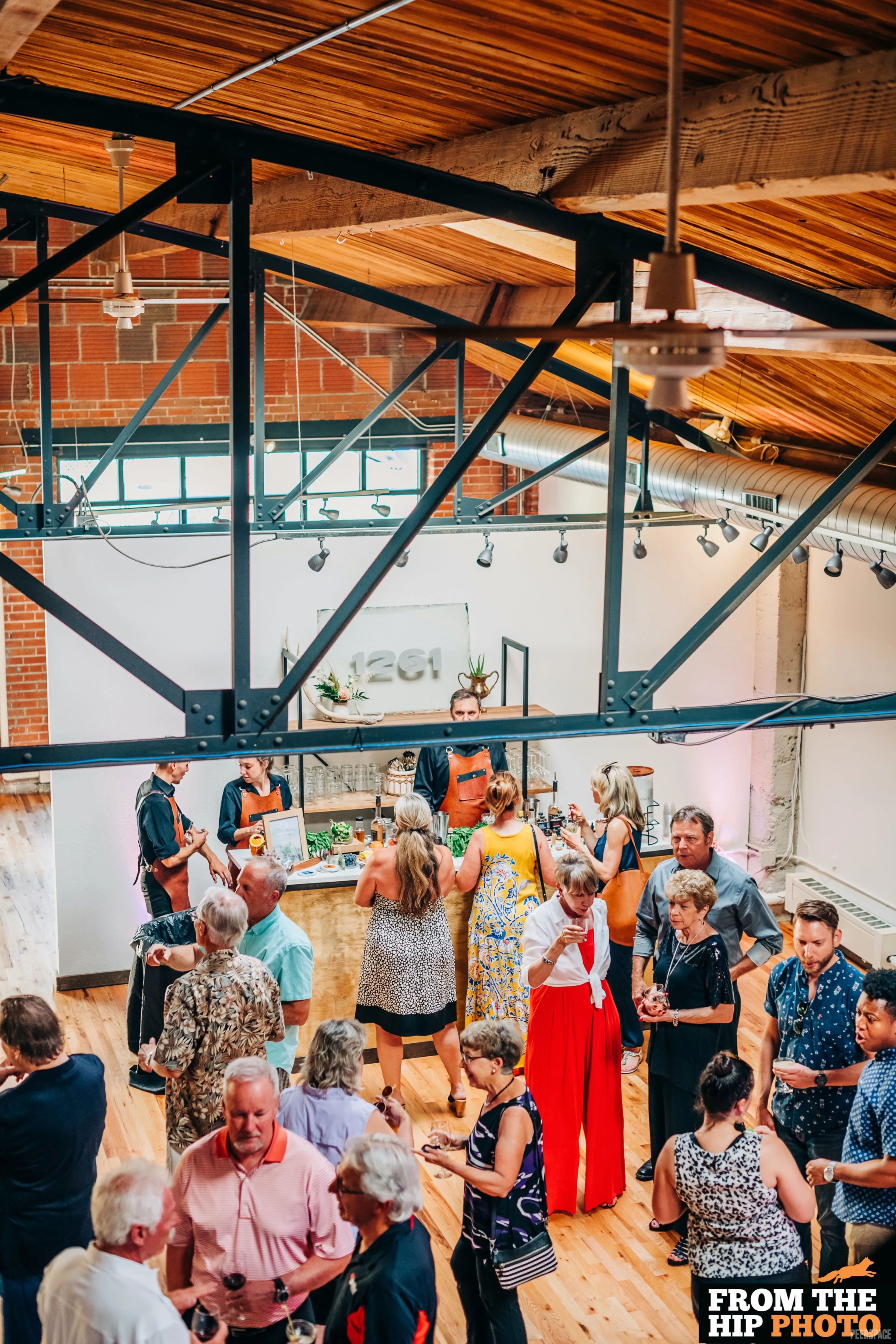Cocktail event at Sterling Event Space — steel trusses, vaulted wood ceiling, and the '1261' wall mark visible