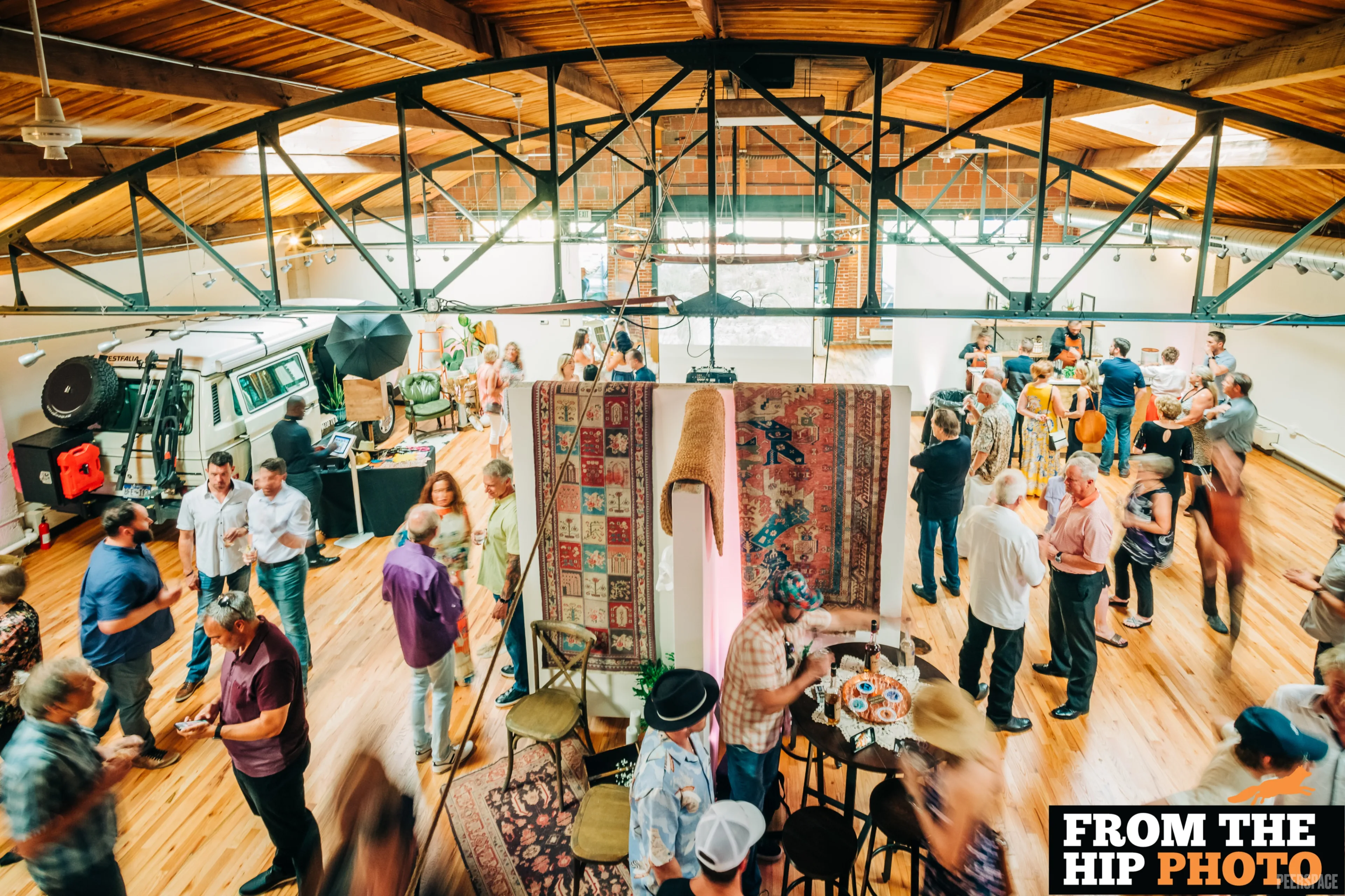 Hosted gallery event at Sterling — rugs hanging beneath the steel trusses and barrel-vaulted wood ceiling