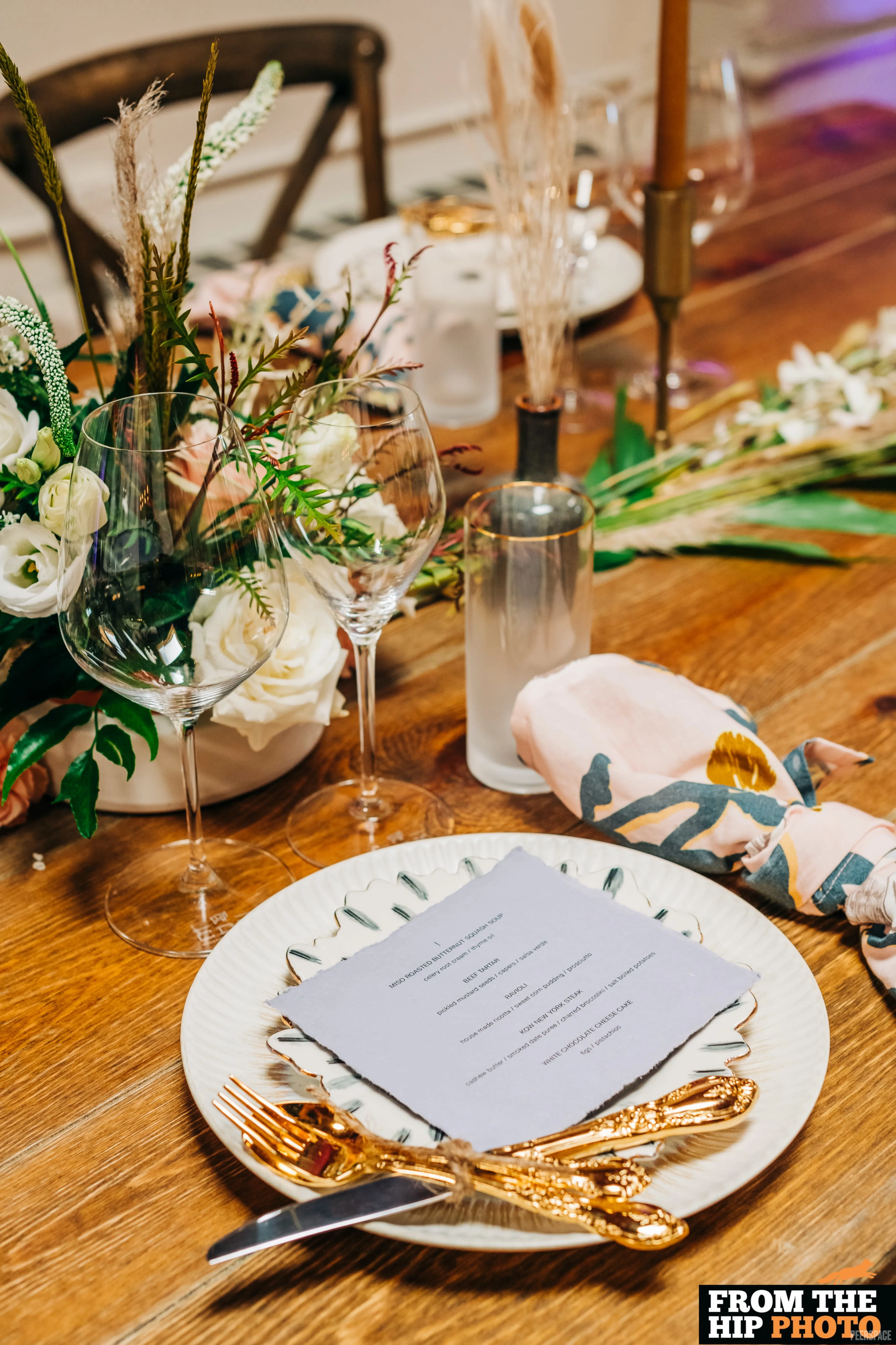Wedding table setting at Sterling Event Space — wood farm table with pampas grass, white roses, and gold flatware