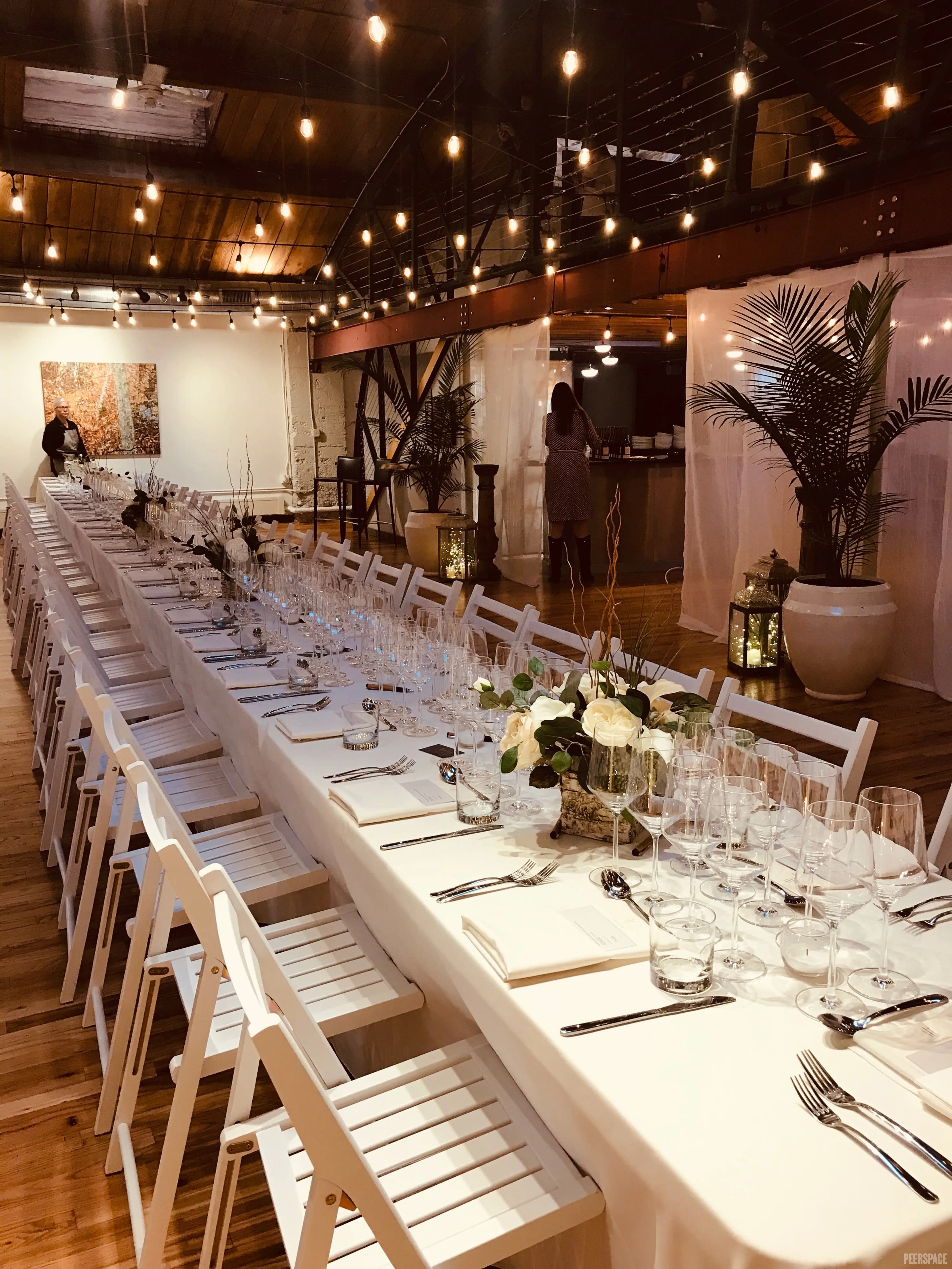 Long communal wedding dinner under Edison string lights, Sterling Event Space Denver